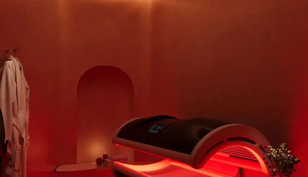 Interior rendering of a red-lit wellness room with a therapy pod and warm accent lighting.
