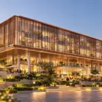 Commercial building with bronze-toned louvers, illuminated glazing and landscaped arrival steps at dusk