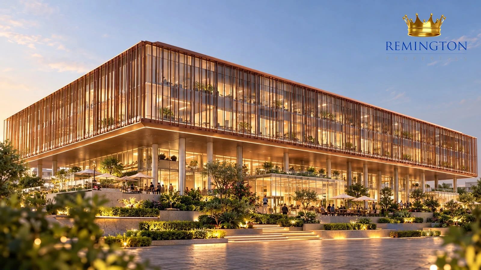 Commercial building with bronze-toned louvers, illuminated glazing and landscaped arrival steps at dusk